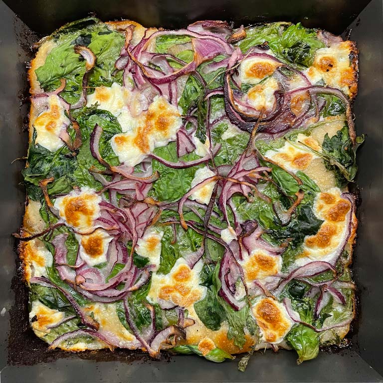 Garlic Cream, Greens, Red Onion and Mozzarella baked in pan.