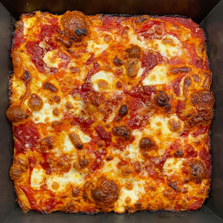 Red Grandma Style Pizza whole in a pan.